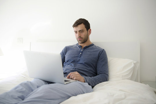 Man using a laptop while relaxing on the bed