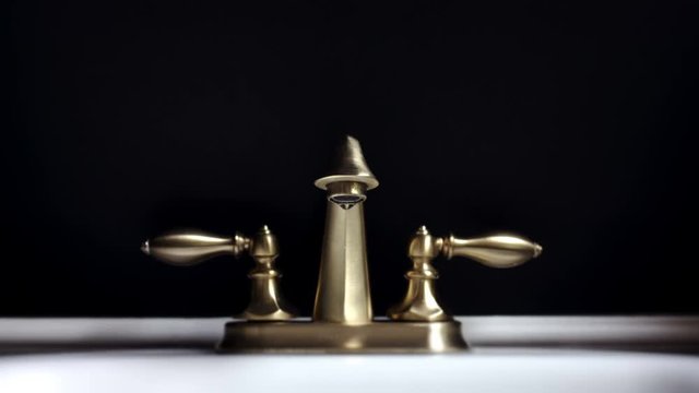 Loopable Dramatic Footage of Leaking Bathroom Faucet Over Black Background.