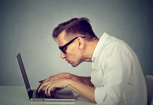 young man in glasses working on computer sitting at desk