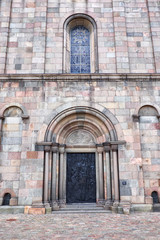 The entrance door and a leaded window, in Viborg Cathedral, build of ashlar granite, sandstone and red stone from the island Fur