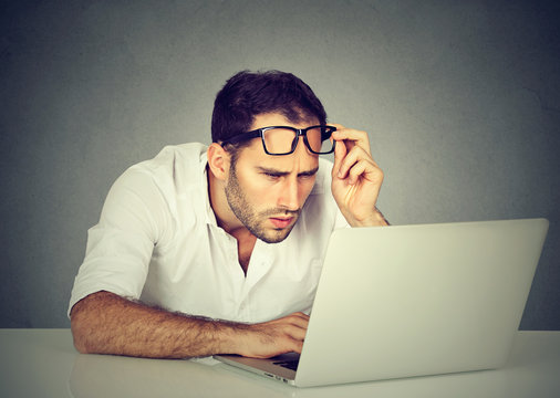 man with glasses having eyesight problems confused with laptop