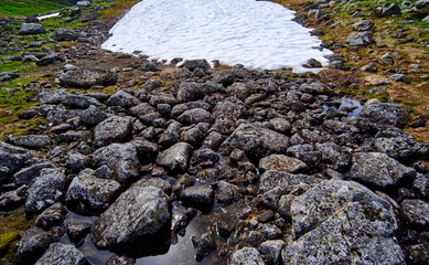 Closeup of a granite stone formation, lying the melted water from summer snow in norway