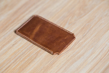 Genuine leather phone case on wood background
