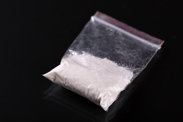 Cocaine in plastic packet on black background