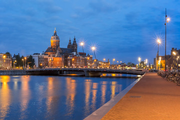 Fototapeta na wymiar Night panoramic city view of Amsterdam canal, bridge and Basilica of Saint Nicholas, Holland, Netherlands. Long exposure.