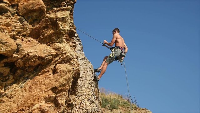 Climber Doing Down The Rope From A Cliff