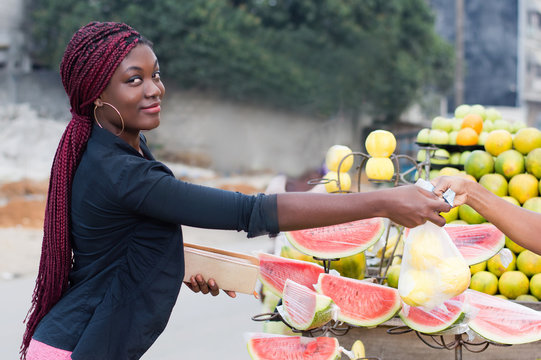 pretty young woman buys food fruits at street market.