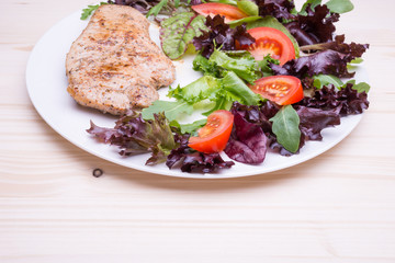 Beef steak with salad and tomato on white plate on beige wooden