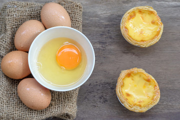 Egg tart custard sweet delicious dessert with fresh eggs on wood background