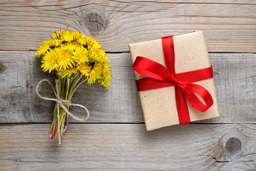 Dandelion flowers and gift box on wooden background