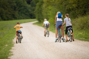 Fototapeta premium Family ride bikes on country road, outdoor in green environment