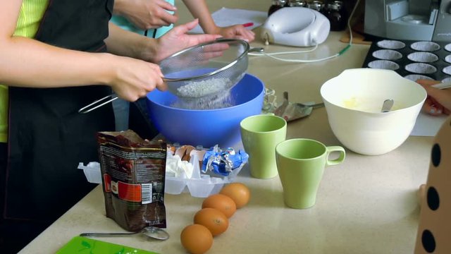 Unrecognizable woman sifting flour using a sieve