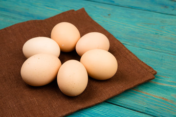 Chicken eggs and brown linen napkin on blue wooden table
