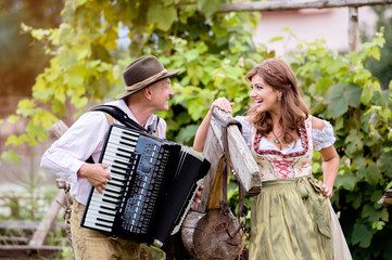 Couple in traditional bavarian clothes with accordion, green gar