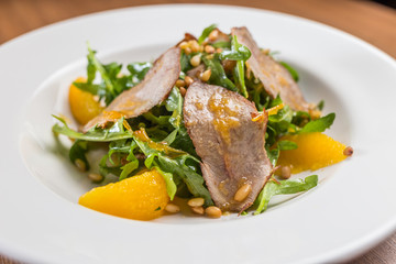 salad with baked duck on white plate
