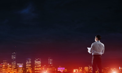 Fototapeta premium Businessman viewing night glowing city