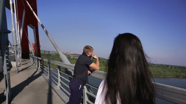 European girl goes to the guy to give support to the false situation. Depression boy. Heavy period of life. Friends support. Woman walk over a bridge to a boyfriend in slow motion and hugs him.