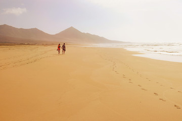 Fototapeta na wymiar A couple walking holding hands on the beach Cofete on Fuertevent