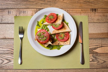 Delicious vegetarian lunches tomato salad Caprese with basil sauce and cheese on a white plate. Serving Table
