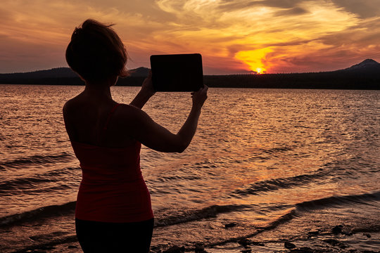 Girl photographing the sunset on the table