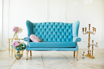 beautiful interior - blue sofa, a glass table and flowers in vas