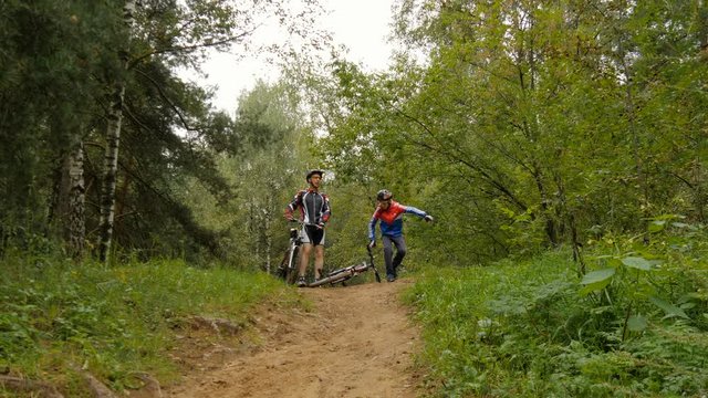 Dad and son go for a drive in the woods on bicycles. Celebrate the victory 