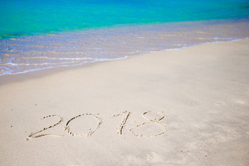 2018 handwritten on sandy beach with soft ocean wave on background