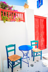 Blue chairs and table on street of typical greek traditional village with white houses on Mykonos Island, Greece, Europe