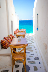 Benches with pillows in a typical greek bar in Mykonos with amazing sea view on Cyclades islands - obrazy, fototapety, plakaty