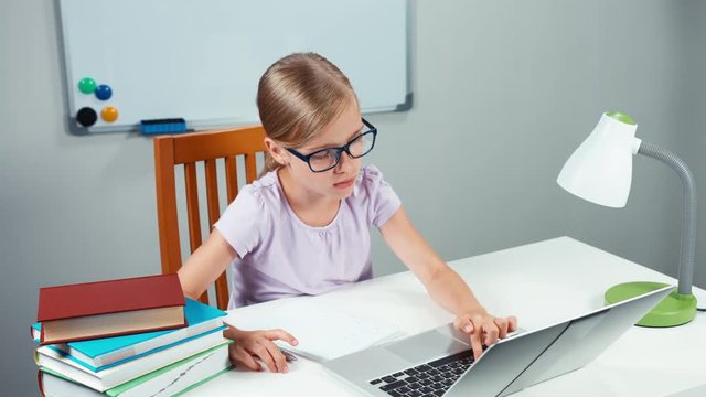 Schoolgirl 7-8 years doing homework in mathematics by computer