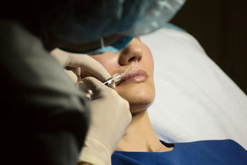 Doctor cosmetologist doing botox injection syringe. The doctor does an injection in the face of the cannula.