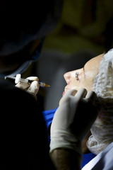 Doctor cosmetologist doing botox injection syringe. The doctor does an injection in the face of the cannula.