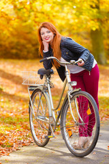 Naklejka na ściany i meble Ginger hair girl with her bike in the park.
