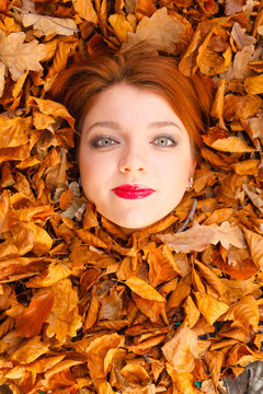Young lady covered by leaves.