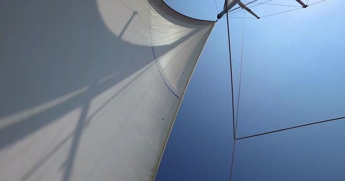 Large yacht sail blowing in the wind on a blue sky day