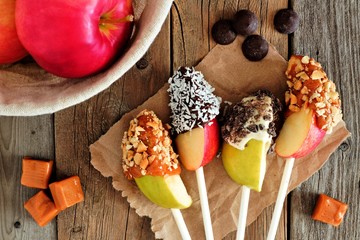 Sweet chocolate and caramel dipped apple slices, scene on a rustic wooden background