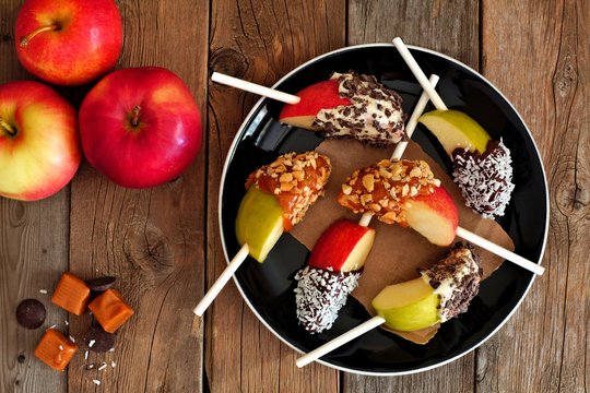 Plate Of Mixed Sweet Caramel And Chocolate Dipped Apple Slices, Overhead Scene On Rustic Wood