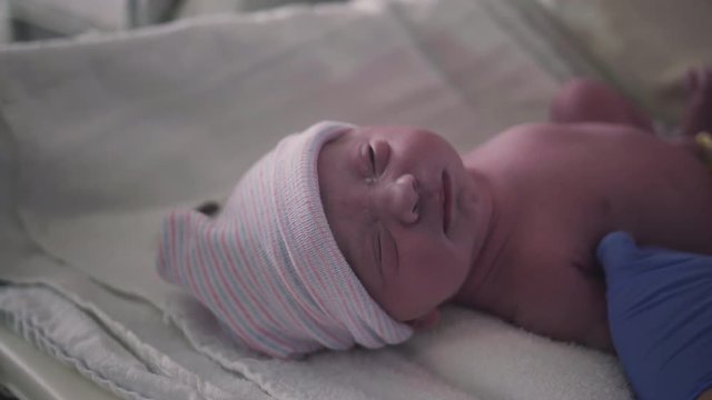 Nurse Puts Stocking Hat on Newborn Newborn Baby Girl Just Born in Hospital