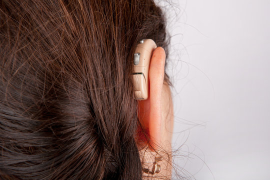Ear of a woman with hearing aid from back
