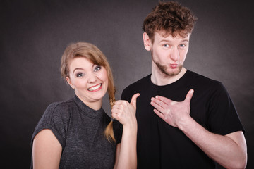 Portrait of joyful couple pointing to man.