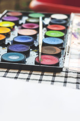 Watercolor equipment, paint, paper and brushes on table