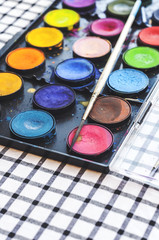 Naklejka premium Watercolor equipment, paint, paper and brushes on table