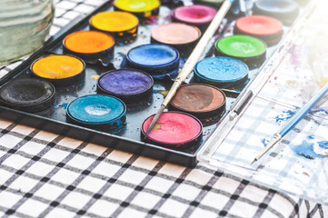 Watercolor equipment, paint, paper and brushes on table