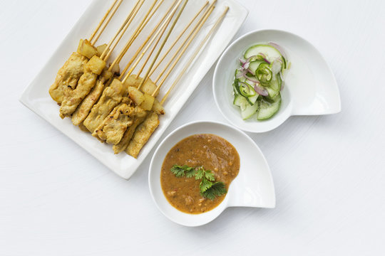 Grill pork satay with peanut sauce and cucumber salsa on white background