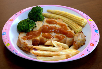 A lovely dish of the pork steak topped with the tomato sauce served with french fried and vegetables.
