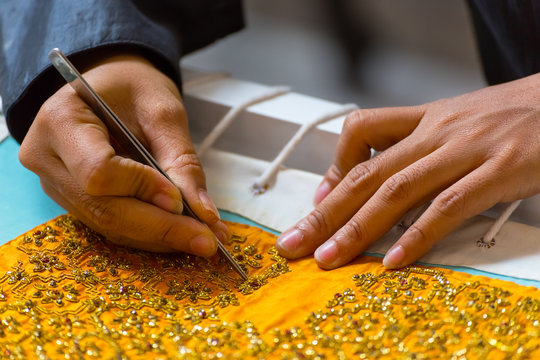 Hands sewing a costume for thai traditional puppet