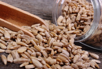 Sunflower seeds spilling out of glass jar. Wooden background