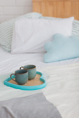 Fototapeta na wymiar Two mugs on a tray white bed, breakfast concept