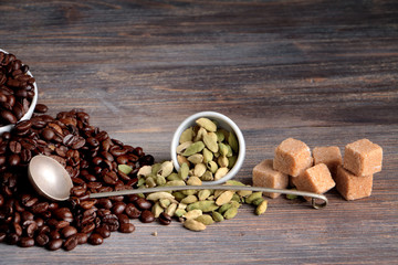 Coffee beans, cane sugar and cardamon seeds  on a wooden table. Special light. Closeup.