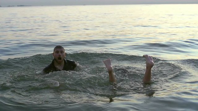 Caucasian man emerges from the sea slowmotion. European girl emerges from under the feet of water slow motion. 20s couple people fleeing into the ocean slo-mo. Guy and woman drowned slow-mo.